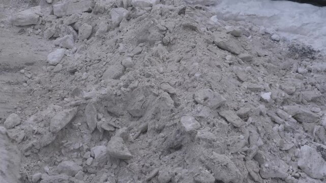 Special machinery clears a huge pile of frozen dirty snow and ice on the road. A front loader uses its bucket to remove the aftermath of a heavy winter snowfall in the city