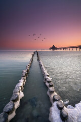 Fototapeta premium old wooden jetty on the beach at the pier in Heringsdorf, Usedom, in winter