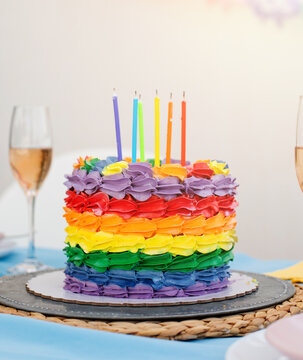 Colorful layered cake with glowing candles on a festive table display