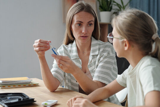 Mother and daughter using glucometer for blood glucose check at home