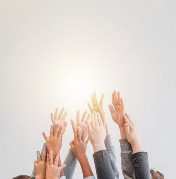 Children enthusiastically raise their hands against a colorful backdrop