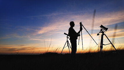 Fototapeta premium Amateur astro-photographer with a telescope and camera on a tripod photographing night sky with stars, planets, Moon and other celestial objects.
