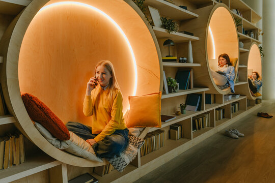 People relaxing with technology in cozy coworking library space