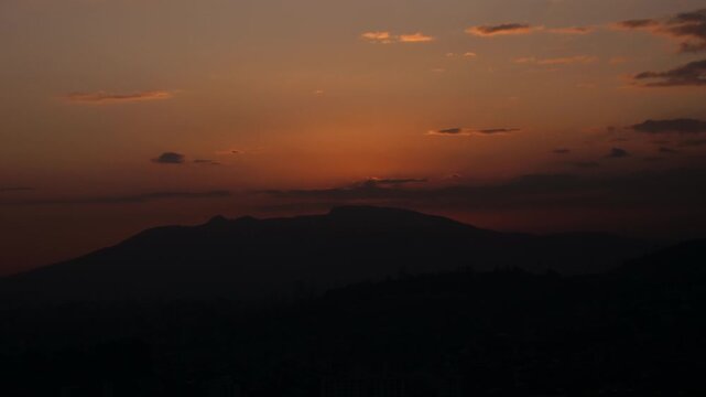 Sun sinking down behind mountain over addis ababa city partly cloudy