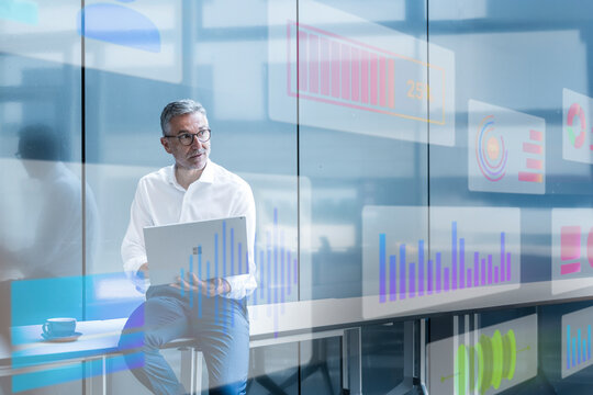 Businessman analyzing digital data with laptop in modern office