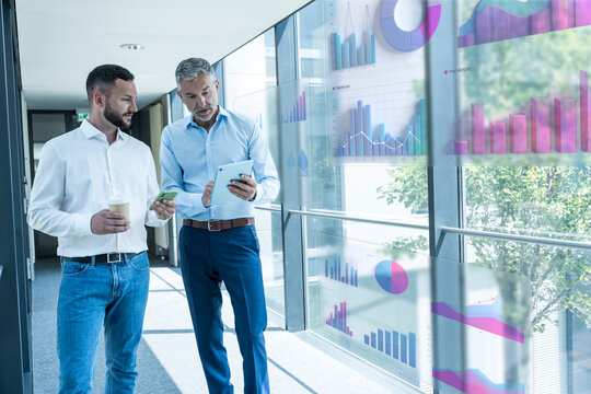 Colleagues analyzing business data with tablet in modern office