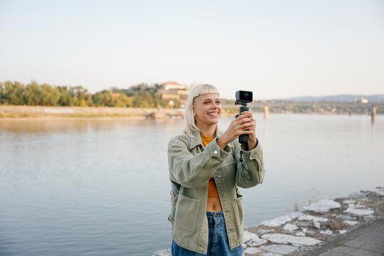 Vlogger smiling and recording video at riverside outdoors