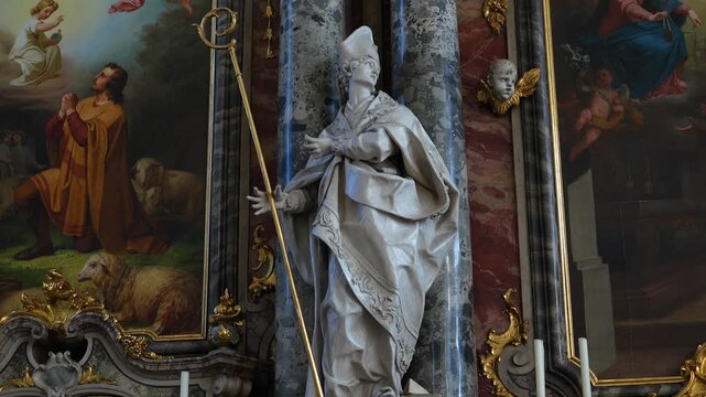 Detailed footage of a statue depicting a holy bishop holding a staff inside the Catholic church.