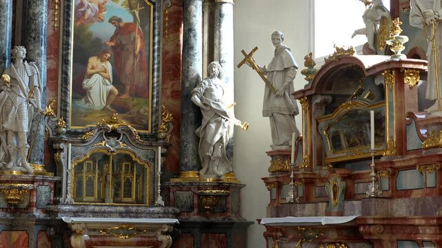 Full view of one of the many side altars featuring religious paintings and golden rococo frames.