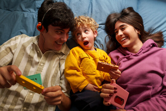 Family enjoying retro music and cassette tapes together on bed