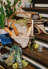 Fototapeta premium Fresh produce basket with assorted fruits and vegetables on wooden staircase with greenery