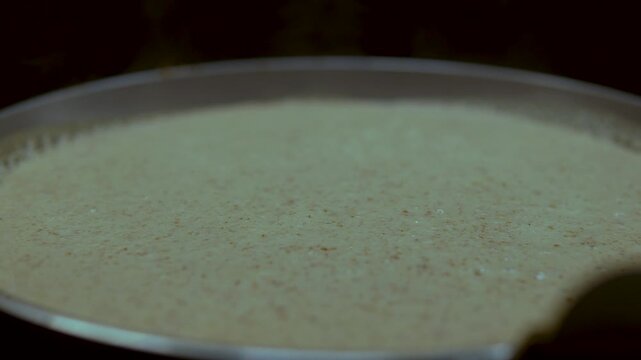Macro shot of liquid pancake batter cooking on a hot griddle surface. Perfect for culinary tutorials, breakfast cooking sequences, and food industry content.