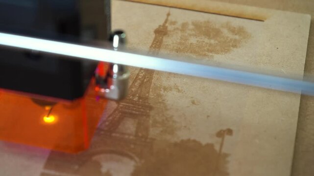 Laser engraves Eiffel Tower on MDF, closeup, focused, precise craftsmanship