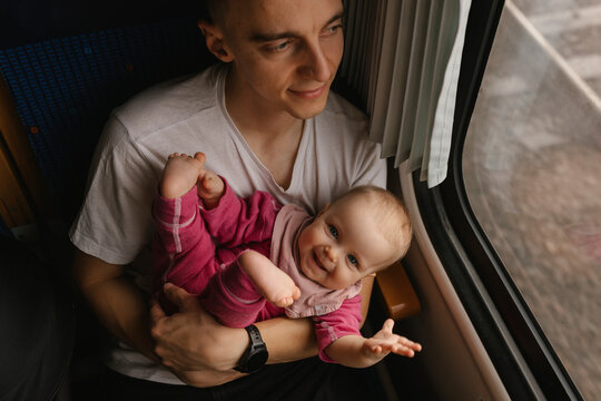 Father holding baby on a train looking out the window travel moment