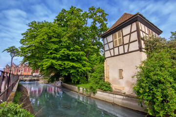 Colorful historic canal houses reflected in quiet water in Colmar.