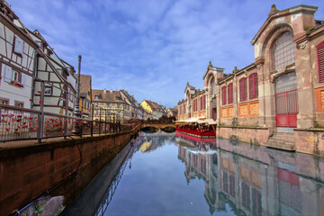 Colorful historic canal houses reflected in quiet water in Colmar.