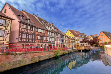Colorful historic canal houses reflected in quiet water in Colmar.