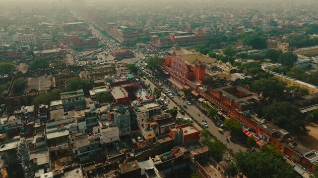 Aerial view of the Hawa Mahal, a stunning pink sandstone palace amidst a bustling city with cars, and rich textures, Jaipur, Rajasthan, India.