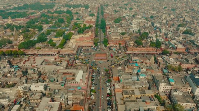 Aerial view of Hawa Mahal, a palace in Jaipur, surrounded by busy streets filled with vehicles and people, exhibiting vibrant colors and textures, Jaipur, Rajasthan, India.