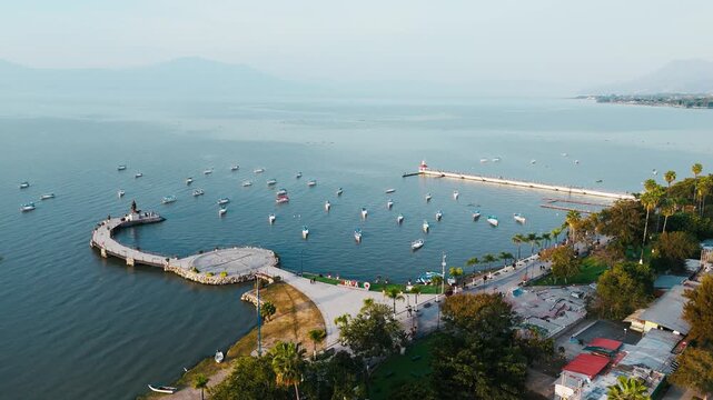 Aerial view of boats dotting the serene waters near the pier and shoreline, where the town meets the lake, Chapala, Jalisco, Mexico.