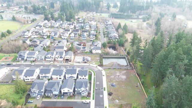 Curved roadway off Kent Kangley Rd borders retention pond and forest buffer near transition zone toward Covington city limits. Mixed roof tones, trimmed lawns, tall evergreens in winter, Kent, WA