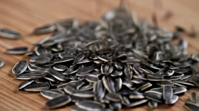 Close-up of sunflower seeds falling onto wooden table, nutritional food concept