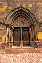 Ornate carved Gothic church doorway in Colmar showing medieval stone sculptures and architecture.