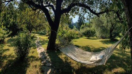 Obraz premium A white woven hammock hangs between two trees in a sunlit garden, with a stone path and lush green lawn. Concept Garden Hammock Photo Shoot, Sunlit Garden, White Woven Hammock, Stone Path