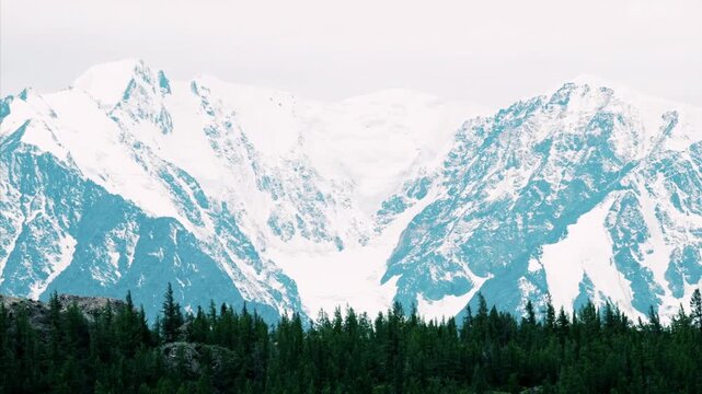 Aerial drone view of snow-covered mountains and forested valley in the Altai Republic, Russia, winter landscape with alpine peaks and frozen nature, horizontal shot, clear daylight, February 2022