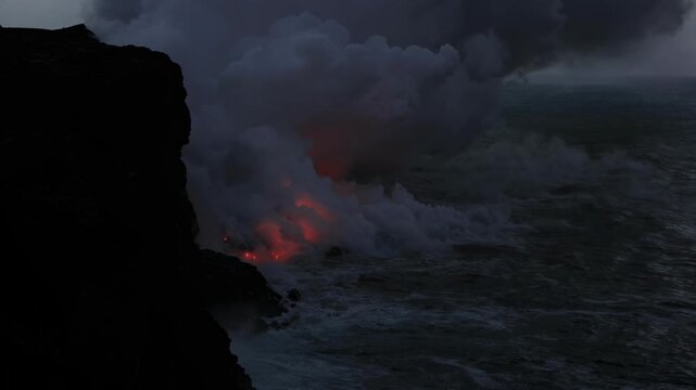 Dramatic volcanic lava flow entering the ocean on the Big Island of Hawaii. Glowing molten lava meets seawater, creating intense steam clouds and fiery red light against a dark coastal landscape.