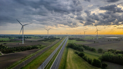 Aerial view of wind turbines and highway in rural Belgium countryside at sunset - renewable energy transition concept © Bjorn B