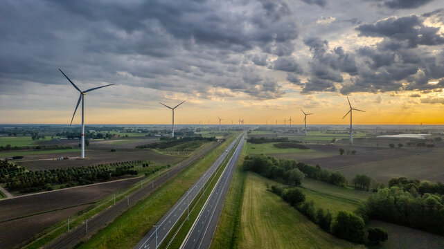 Aerial view of wind turbines and highway in rural Belgium countryside at sunset - renewable energy transition concept