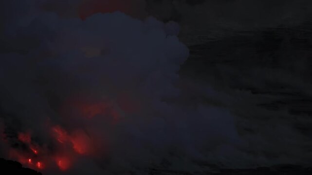 Dramatic volcanic lava flow entering the ocean on the Big Island of Hawaii. Glowing molten lava meets seawater, creating intense steam clouds and fiery red light against a dark coastal landscape.