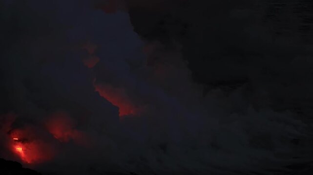 Dramatic volcanic lava flow entering the ocean on the Big Island of Hawaii. Glowing molten lava meets seawater, creating intense steam clouds and fiery red light against a dark coastal landscape.
