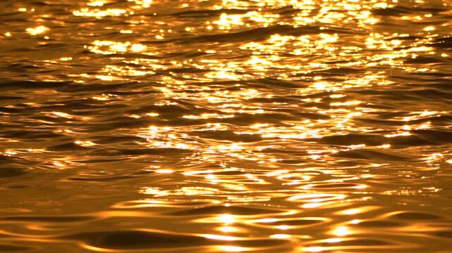 Water sunset glittering reflections create a mesmerizing golden abstract background texture of liquid light