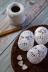 Three white hand-crocheted eggs lie in a rustic woven basket, perfect for Easter, spring decorations, handmade crafts, and cozy home d&eacute;cor with soft artisanal textures.