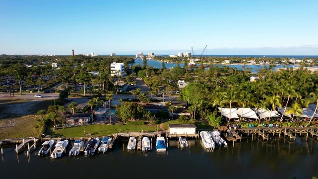 Aerial view of boats docked near a restaurant with white canopies, fringed by palm trees and waterways, Jupiter, Florida, United States.