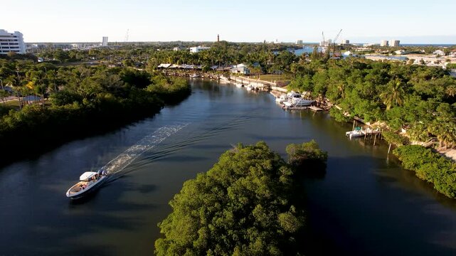 Aerial view of a serene waterway with lush green trees and docks, contrasting with the dark water, Jupiter, Florida, United States.