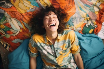 Fototapeta premium Young person laughing with eyes closed lying on colorful bed sheet