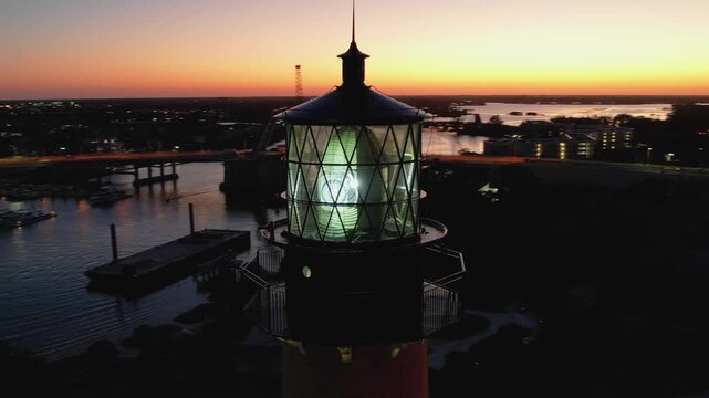 Aerial view of Jupiter Lighthouse Park at dusk, the lighthouse casting a bright light against the dark sky, Jupiter, Florida, United States.