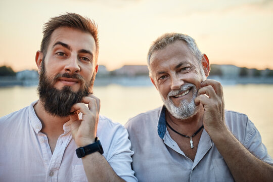 Portrait of smiling father and adult son scratching their beards