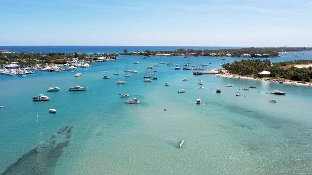Aerial view of boats sailing on clear blue waters near docks and buildings, where the sky is blue and clear, Jupiter, Florida, United States.