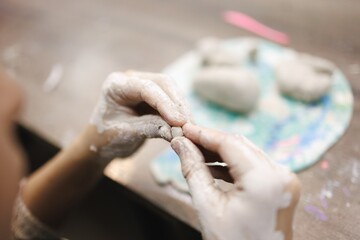 Obraz premium Hands mold clay with care on a wooden table during a creative pottery making session at home