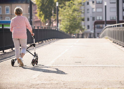 Senior woman with wheeled walker on footbridge