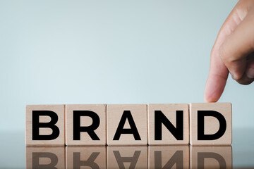 Business marketing and corporate identity concept. Hand arranging wooden blocks with word Brand. Symbol of reputation, product launch, company vision, and customer loyalty.
