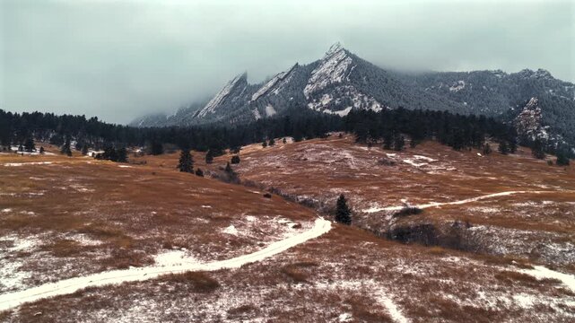 Winter Chautauqua Park Flat Irons Mountain snowing snow flakes snowfall aerial drone Colorado USA dusk sunset low clouds grass snow covered Rock formation walking loop trail Bear Peak forward upwards