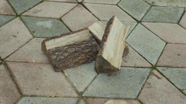Wood logs arranged on a patterned stone surface with an axe poised above, showcasing the process of chopping firewood in a backyard setting