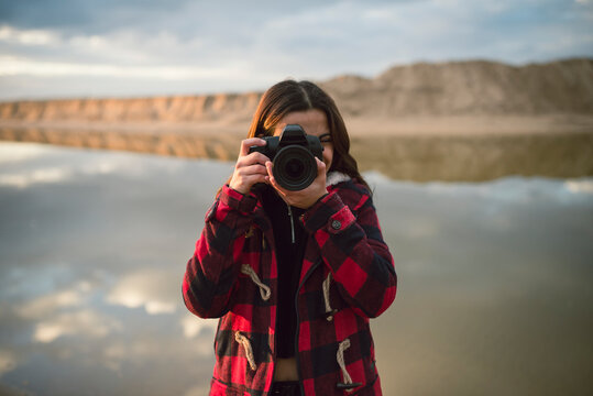 Young woman taking picture with camera on the beach