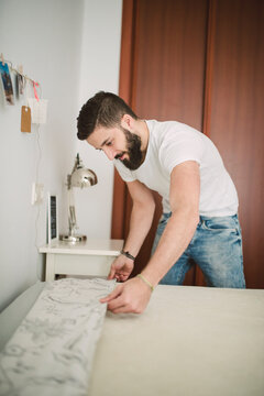 Young man making the bed at home