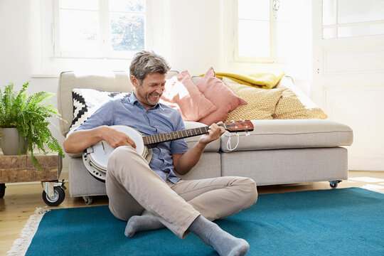 Man sitting on floor, playing the banjo
